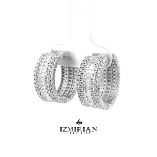 Angled view of baguette and pavé diamond huggie earrings
