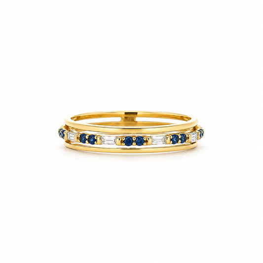 A yellow gold eternity ring featuring a channel-set row of round-cut blue sapphires and baguette-cut clear stones, shown on a clean white background.