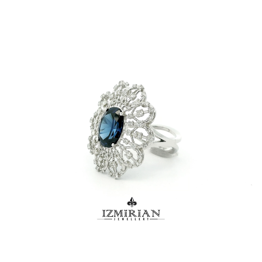Angled view of ornate blue sapphire and diamond halo ring in white gold