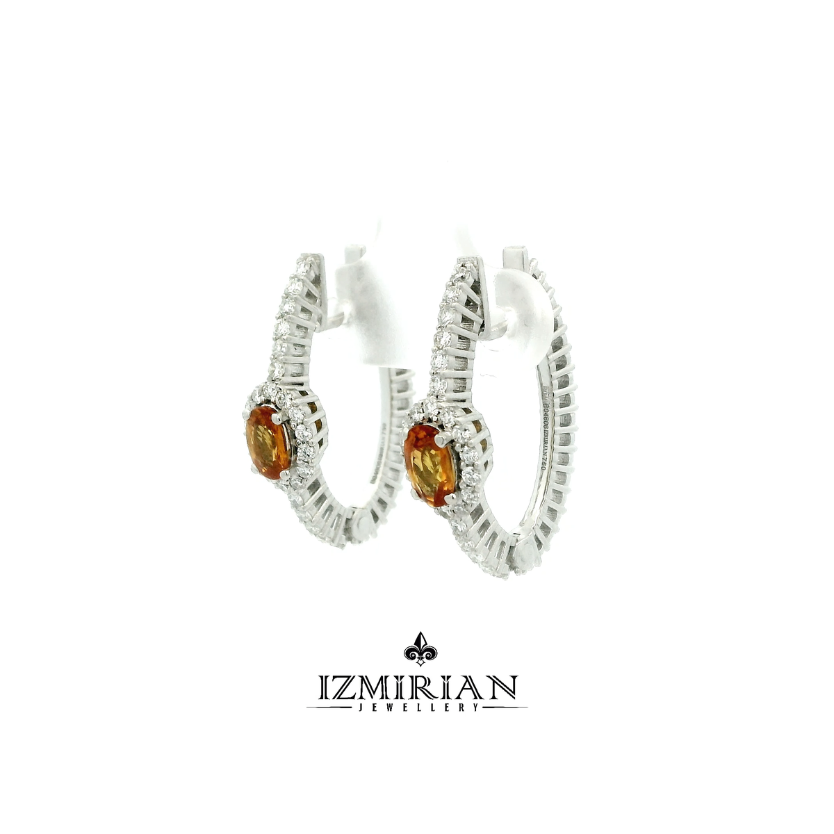 Angled view of orange sapphire earrings with diamond halo and drop design