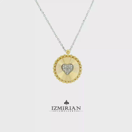 Diamond heart medallion pendant in yellow and white gold shown in motion