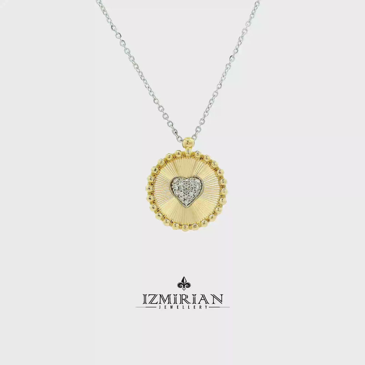 Diamond heart medallion pendant in yellow and white gold shown in motion