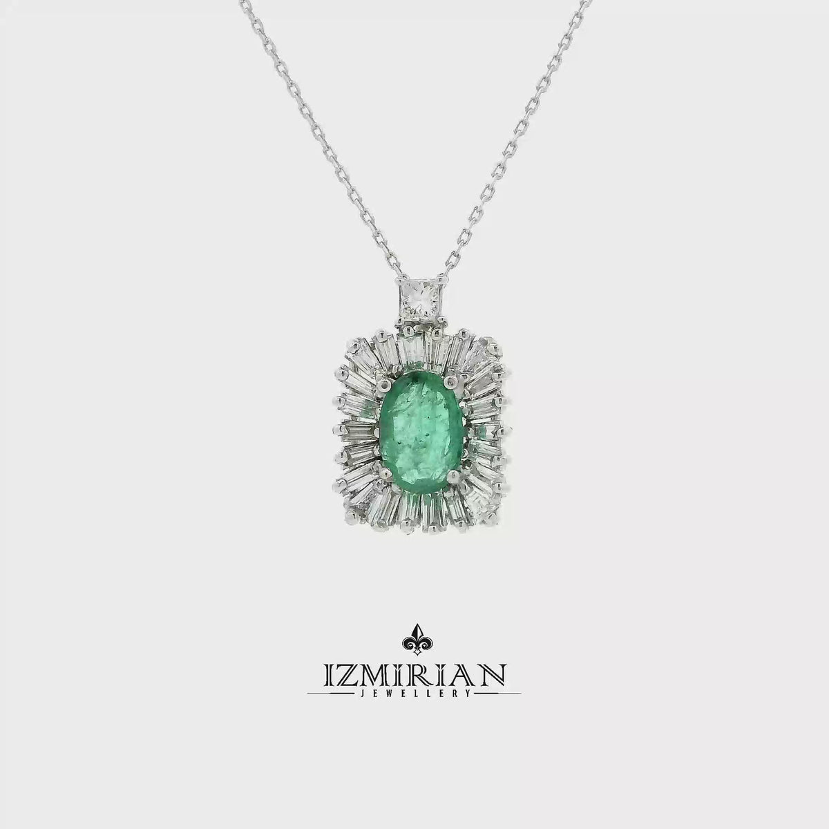Emerald and diamond halo pendant in white gold shown in motion
