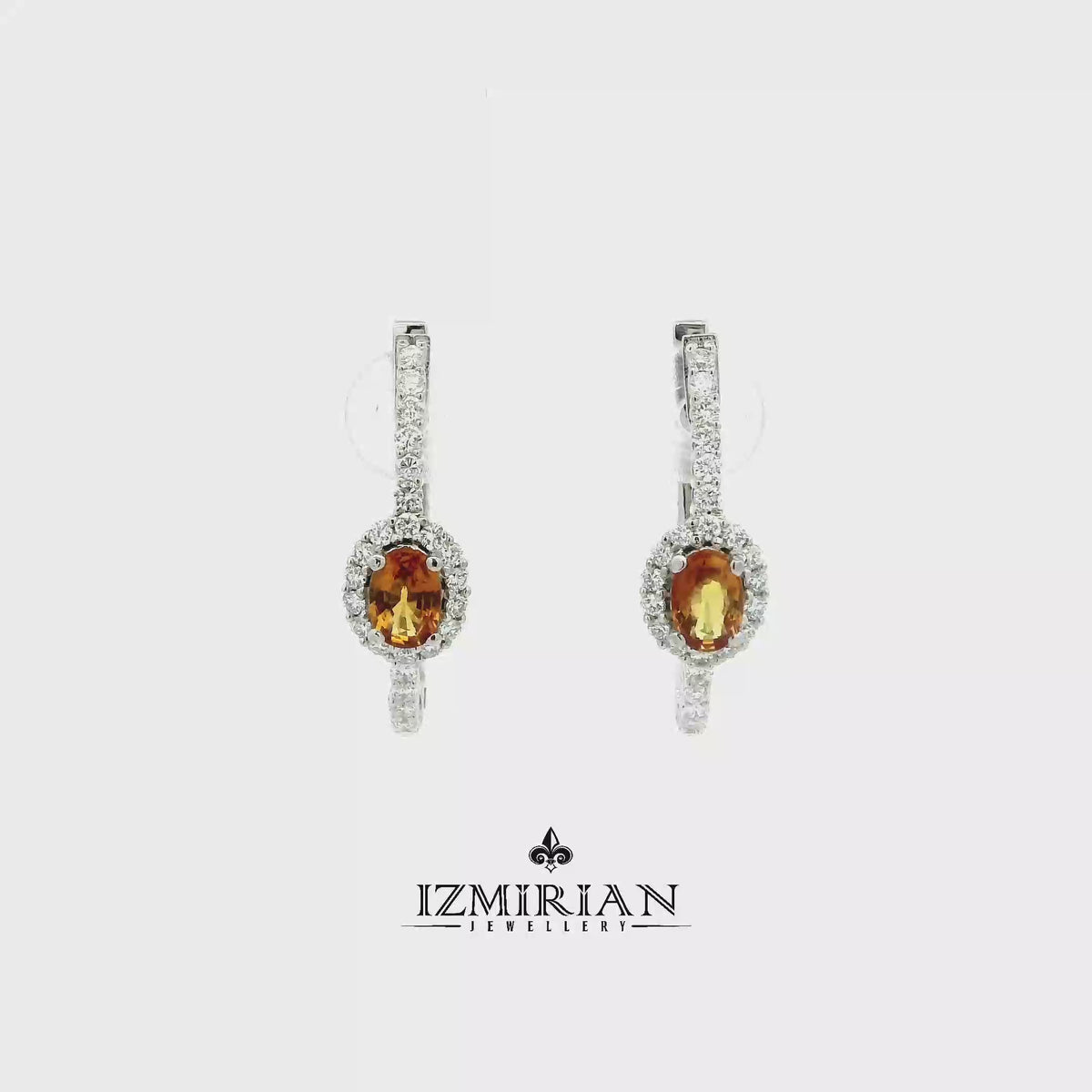 Orange sapphire and diamond drop earrings in white gold shown in motion
