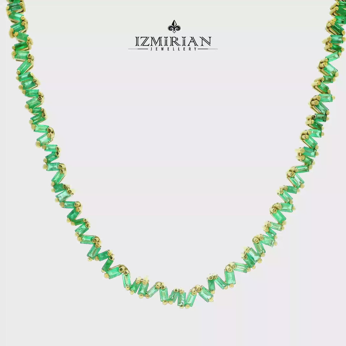 Zigzag emerald baguette necklace in yellow gold shown in motion