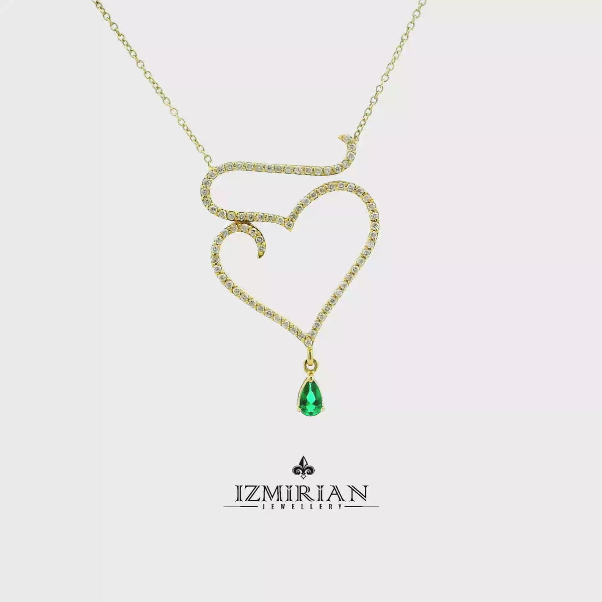 Emerald heart diamond pendant necklace in yellow gold shown in motion